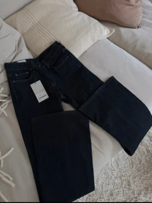 Mörkblåa flare jeans avora - Säljer ett par mörkblå bootcut jeans från Weekday. Jeansen har hög midja, klassisk femficksdesign och är tillverkade i ett kraftigt denimtyg. Snygg passform som sitter tight upptill och släpper ut över benen. Perfekta till en trendig streetstyle-look.
