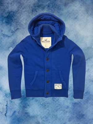Vintage Hollister Hoodiejacka - Säljer denna feta Hollister hoodiejackan, fodrad inne så varm och skön till det kalla vädret | Väldigt bra skick förutom lite tecken på användning se sista bild | Storlek S | Längd ≈ 65cm, Bredd armhåla - armhåla ≈ 52cm | Modell 175cm, 68kg
