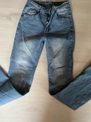 Blå jeans från SHEIN - Ett par klassiska blå jeans från SHEIN med lätt tvättade detaljer och raka ben. Jeansen har fem fickor, bälteshällor och stängs med knapp och dragkedja. Perfekta för en avslappnad och trendig look.