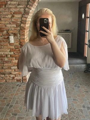 Vit studentklänning  - Söt vit kortklänning, öppen rygg och lätt transparenta, fladdriga kortärmar. Klänningen har rynkade detaljer i midjan och ett knyt i ryggen för extra bra passform. Aldrig använd 🌸🤝