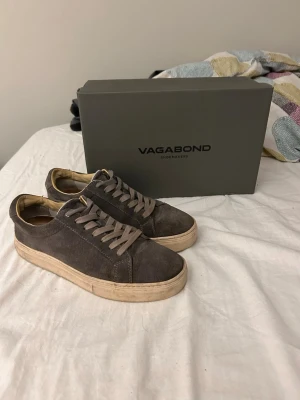 Vagabond mocka sneakers  - Snygga gråa sneakers från Vagabond i mjuk mocka med beige sula och matchande gråa skosnören. Klassisk låg modell som passar perfekt till jeans eller chinos. Kommer med originalkartong och kvitto.