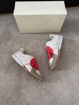 Maison Margiela Japan Gats - Säljer ett par väldigt sällsynta och unika Gats, Japan. En tidlös och stilren sneaker som passar perfekt till både casual och mer dressade outfits. Klassisk design med premium läder och den ikoniska Margiela-känslan.  🔹 Märke: Maison Margiela 🔹 Modell: Replica / GAT 🔹 Skick: Nyskick (se bilder) 🔹 Storlek: 43 🔹 Färg: Vit/Röd/Grå 🔹 Material: Äkta läder 🔹 Nypris: ca 14 000kr  Alltid väl omhändertagna och sparsamt använda. Perfekt för dig som vill ha en exklusiv sneaker som aldrig går ur stil.