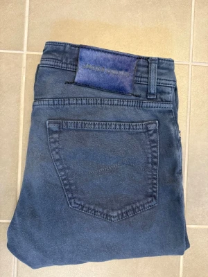 Mörkblå jeans från Jacob Cohën - Snygga mörkblå jeans från Jacob Cohën med klassisk femficksmodell och raka ben. Jeansen har en unik blå patch med logga bak i midjan och är tillverkade i mjukt denimtyg för en bekväm känsla. Perfekta för dig som gillar stilrena och tidlösa jeans.