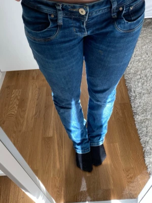 Blå bootcut jeans från LBT - Säljer ett par klassiska blå bootcut jeans från LBT med fem fickor och normalhög midja. Jeansen har en snygg tvätt och är tillverkade i stretchigt denim för skön passform. Perfekta till vardagslooken och lätta att matcha med olika stilar.