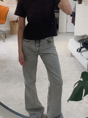 Gråa utsvängda jeans - Säljer ett par gråa jeans med utsvängda ben. Jeansen har klassisk femficksmodell och är tillverkade i ett tvättat denimtyg.