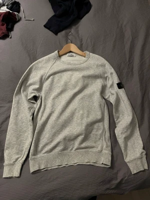 Stone island sweater - Stone Island i klassisk grätt, 100% äkta. För att bevisa äktheten finns en QR-kod på en av bilderna. QR-koden är dock täckt i annonsen för att förhindra att den blir ogiltig om flera skannar den. Skicka ett meddelande om duär intresserad, så skickar jag koden direkt till dig! Detaljer: • Marke: Stone Island • Färg: grått • Storlek: passar som S • Skick: 7/10 • Material: Bekvamt och slitstarkt tyg Tröjans ikoniska Stone Island-kompasslogotyp på vänster ärm gör den igenkännbar och ger en exklusiv 