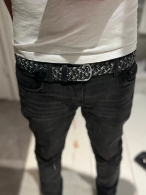 Onewear blå och grått flätat bälte - Snyggt flätat bälte i blått, grått och vitt med detaljer i skinn. Bältet har ett klassiskt metallspänne och passar perfekt till jeans eller chinos. Den flätade designen gör det enkelt att justera längden för bästa passform. Inga synliga skador.                                                                 Storlek: 90                                                                         Nypris: 349 kr