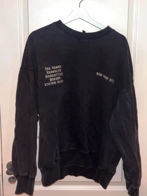 Svart oversized sweatshirt H&M - Cool svart oversized sweatshirt från H&M med tryck på bröstet där det står 'New York City' och namnen på stadsdelarna. Mjuk bomullskvalitet och avslappnad passform, perfekt för en chill look.