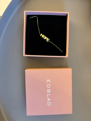 Guldigt HOPE-armband från Edblad - Snyggt armband från Edblad i guldtonat metall med texten HOPE som detalj. Säljer då det inte kommer till användning. 