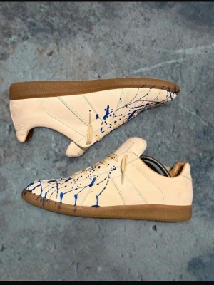 Maison Margiela paintsplatter gats -  Maison Margiela gats med blå paintsplatter. Extemt bra skick, nästan deadstock. En pytteliten scuff på ena hälen och ena replica taggen är lite sne pga användning. Från ca 2016 och tillverkas inte längre. Dessa har sålts för 5k plus på Grailed i sämre skick. Storlek 43 men passar en 42-44 också. Självklart äkta. Kom gärna med frågor 😊