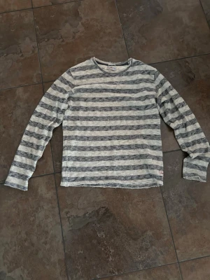 Randig stickad tröja Jack & Jones - Grå och vitmelerad stickad tröja från Jack & Jones Originals. Tröjan har horisontella ränder, rund halsringning och långa ärmar. Tillverkad i mjukt material som passar perfekt för en avslappnad stil.