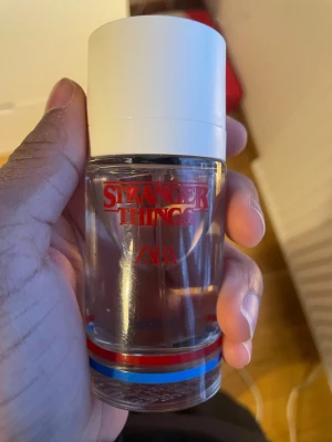 Stranger Things parfym från Zara - Cool parfym från Zara i samarbete med Stranger Things. Flaskan är genomskinlig med vitt lock och har röda, blå och silverfärgade detaljer längst ner. Texten 'Stranger Things' syns tydligt i rött på framsidan. Perfekt för dig som gillar unika dofter och snygg design. Och den luktar som frukt loops.
