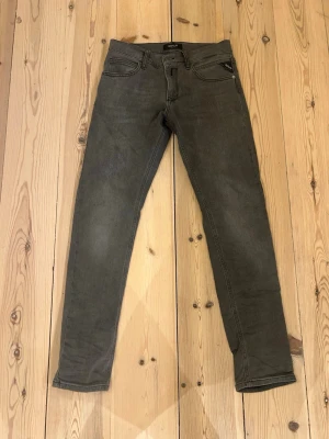 Grå slim fit jeans från Replay - Snygga grå slim fit jeans från Replay med klassisk femficksmodell och diskreta sömmar på bakfickorna. Jeansen har en modern passform och är tillverkade i mjukt denimtyg med lite stretch för extra komfort. Perfekta för en avslappnad och trendig look. Köpte dem för någon månad sen knappt använda. 