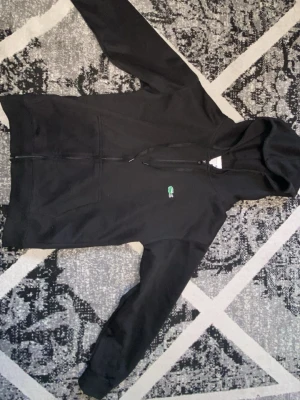 Svart zip hoodie Lacoste - Inte mycket använd och därför har den inga defekter. Passar även S. 
