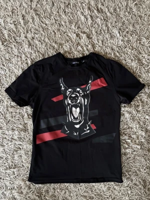 Antony Morato T-shirt - Antony Morato t-shirt med ett stort tryck av en hund på framsidan och röda samt svarta grafiska linjer. T-shirten har rund hals och korta ärmar.