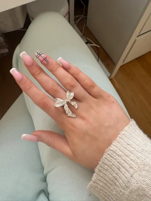 Silvrig rosettring med stenar - Säljer en ring i form av en stor rosett i silverfärg. 