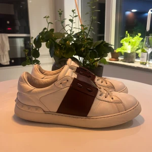 Valentino open - Säljer ett par Valentino Open i vitt och vinrött 100% äkta och i bra skick – bara normalt bruksslitage, inget större. Väldigt bekväma och passar till det mesta.  📏 Storlek: 43 🎨 Färg: Vit/vinröd 🧾 Nypris: ca 6 000–7 000 kr  Skickas snabbt och välpackat. Hör av dig om du vill ha fler bilder eller frågor!