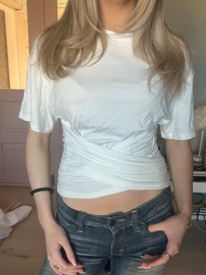  omlottopp med knyt i midjan - Säljer en super snygg vit topp med omlottdesign och knyt i midjan. Går att knyta både fram och bak, skriv för fler bilder eller frågor!!