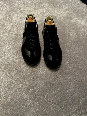 Maison margiela  - Säljer ett par svarta maison margiels skor med låg profil som passar till allt. Storleken är precis som en 44 ska vara. Skorna är gjorda i mocka och svart läder vilket ger en snygg finish. Tveka inte på att komma med prisförslag eller diverse frågor! 