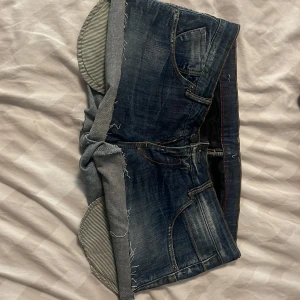 Mörkblå jeansshorts med broderade detaljer - Säljer ett par mörkblå jeansshorts med råa kanter och broderade detaljer i gult och orange på bakfickorna.   Jag har satt in snören på insidan så att dom ska sitta bättre men dom går att ta bort och syns inte. Jag har klippt dom själv  ingen lapp men det står Denim & Denim på knappen. 
