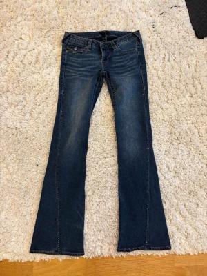 True religion low rise flare jeans med stenar - Säljer mina as snygga true religion jeans med stenar längst sidorna, de är i storlek 25 (xs) men skulle säga att de är lite stora i midjan! Midjemått: ca 35 cm Innerbenslängd: ca 80 cm