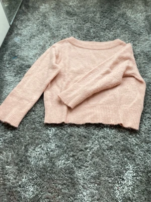 Ljusrosa stickad tröja Gina Tricot - Supersöt ljusrosa stickad tröja från Gina Tricot. Tröjan har en croppad passform, bred ribbad mudd i nederkant och vid ärmslut samt rund halsringning. Perfekt för att addera en mjuk och trendig touch till din outfit.