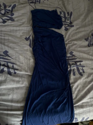 Marinblå långklänning Zara - Marinblå långklänning från Zara med smickrande drapering längs sidan. Klänningen har en elegant och stilren look, perfekt för speciella tillfällen. Tillverkad i ett mjukt och följsamt material.