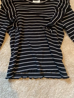 Svartvit randig långärmad topp - Söt, svart långärmad topp från Kappahl med vita horisontella ränder. Toppen är ribbad och har en klassisk rund halsringning. Perfekt att styla med jeans eller kjol för en chill look.