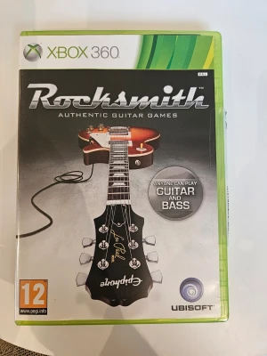 Rocksmith till Xbox 360 - Rocksmith är ett musikspel till Xbox 360 där du kan koppla in en riktig gitarr eller bas och spela över 50 rocklåtar. Omslaget är svart med en bild på en Epiphone Les Paul-gitarr och spelet har PEGI 12. Perfekt för dig som vill lära dig spela gitarr på ett kul sätt.