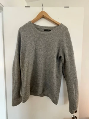 Grå stickad tröja med armbågslappar - Säljer denna snygga Ljung tröja i storlek S, 100% bomull. Den är använd flera gånger men har mer att ge. På armarna där bak ska det egentligen sitta två stycken lappar i läder men nu är det bara märket kvar då de har lossnat. Hör av dig ifall du undrar något. 
