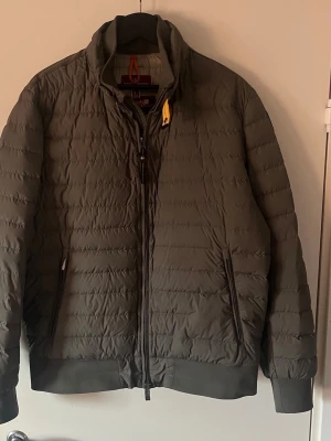 Parajumper dunjacka  - Mörkgrön dunjacka från Parajumper med klassisk gul detalj vid kragen. Jackan har dragkedja framtill, två sidofickor med dragkedja och ribbade muddar vid ärmslut och nederkant. Lätt vadderad och perfekt för våren nypris ca 5000  pris kan diskuteras vid snabb affär :)