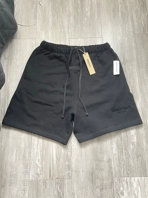 Essentials Sweat Shorts – Helt Nya (Tags kvar) - Säljer nu ett par helt oanvända Essentials shorts (Fear of God) i färgen svart. Detta är den klassiska sweatshirt-modellen i tjockt och skönt material, perfekta för sommaren eller hemmahäng. 