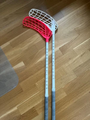 Exel innebandyklubbor - Säljer nu 2st vita Exel Shock Absorber 2.6 innebandyklubbor. Båda klubborna är 96cm långa och har 26 flex. På den ena sitter ett helt nytt left neon rosa Air blad i PP plast. På den andra sitter ett left vitt E-fect blad i PP plast som inte är använt mycket. Klubban med vitt blad har ett slagmärke (se sista bilden) men utöver det är de i väldigt fint skick. Vid frågor eller funderingar är det bara att höra av sig. Pris kan diskuteras.
