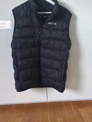 Svart dunväst från Nicce - Säljer nu min Nicce väst då den inte kommer till användning längre. Bra skick inga defekter osv slm nyskick. Stilren passar till mycke. Nypris 1000kr