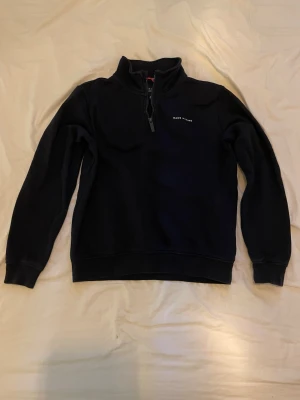 Mörkblå fleece från Race Marine - Mysig mörkblå fleece med halv dragkedja från Race Marine. Tröjan har hög krage och diskret logga på bröstet. Perfekt för lager-på-lager och chill dagar. Klassisk och enkel design som funkar till det mesta.