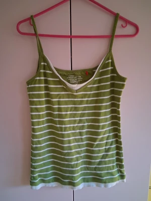Grön- och vitrandig linnetopp Esprit - Snygg grön linnetopp från Esprit med vita horisontella ränder och smala axelband. Toppen har v-ringning med vit kant och är perfekt för varma dagar. Mjuk bomullskvalitet och avslappnad passform.