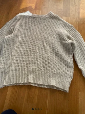 Vit stickad tröja med grov struktur - Säljer en vit stickad tröja med grov, lite oversized struktur och rund hals. Tröjan har långa ärmar och breda ribbade muddar vid ärmslut och nederkant. Perfekt för lager-på-lager och chill dagar.