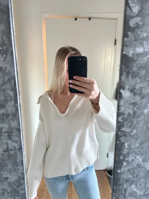 Vit/beige stickad tröja med krage Gina Tricot - Snygg vit/begie lite tjockare stickad tröja från Gina Tricot med lite bredare krage och v-ringning. Tröjan har långa ärmar och ribbad nederkant vid ärmarna och tröj slutet. Tröjan har även en slits vardera sida 