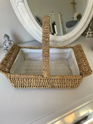Korg nätt och metall  - Flätad korg i naturmaterial med ett praktiskt handtag. Korgen har ett vitt tygfoder inuti. Perfekt för förvaring eller som en dekorativ inredningsdetalj. Korgen den liten tyngd eftersom den är gjort av metall ock fläta korg