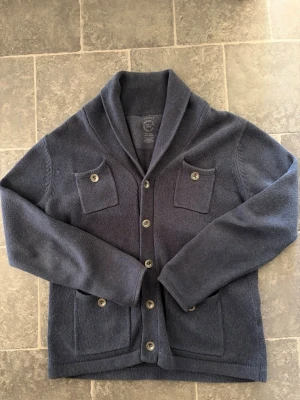 Stickad Cardigan - En stilren cardigan i färgen blå! Den är använd men i bra skick! Pris går att diskutera och skriv om du har frågor!