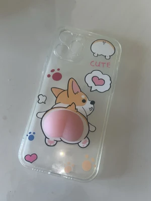 Gulligt mobilskal - Säljer ett genomskinligt mobilskal med en söt tecknad corgi och 3D-detalj. Skalet är till IPHONE 12 PRO och är aldrig använt💓
