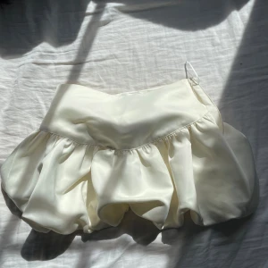 Krämfärgad ballongkjol från Gina Tricot - Supersnygg ballongkjol i krämfärgad satin från Gina Tricot. Aldrig använt - helt nytt skick.