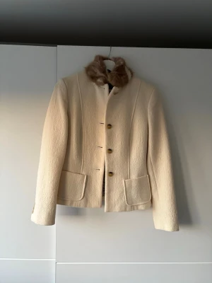 Max Mara ulljacka med äkta päls - Elegant och tidlös jacka från Max Mara i en fin beige/ krämfärgad nyans. Finns inte langre att köpa (2005-2015) * Äkta lyxplagg * Äkta pälskrage (väldigt mjuk och varm) * Högkvalitativ ull * Klassisk, figursydd modell Helt som ny använd max 2/3 gånger passar xs/xxs
