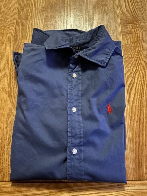 Blå skjorta från Polo Ralph Lauren - Klassisk blå skjorta från Polo Ralph Lauren med relaxed fit. Riktigt snygg och passar med det mesta! Hör av er vid funderingar 😃