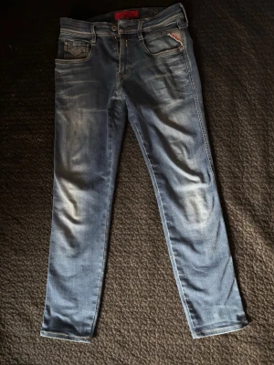 Replay Anbass  - Snygga ljusblå jeans i slim fit-modell med slitna detaljer och klassiska fem fickor. Jeansen har en något tvättad look och raka ben. Perfekta för en avslappnad och trendig stil. Strl 29/32 ljusblå färg. Vid frågor är de bara höra av sig