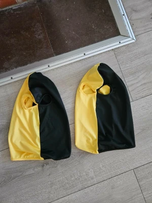 NY 1 svartgul AIK balaklava  - Tvådelad 1 balaklava i svart och gult med två ögonhål. Tillverkad i ett stretchigt, mjukt material som sitter tajt mot huvudet. Perketa for AIK fans