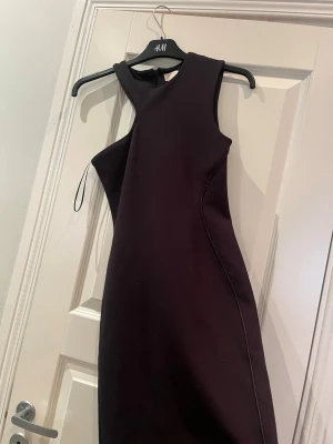 Svart oneshoulder klänning H&M - Snygg svart oneshoulder klänning från H&M med figurnära passform. Klänningen är ärmlös och har en stilren, minimalistisk design som passar perfekt till olika tillfällen. Tillverkad i ett stretchigt material för en bekväm känsla.