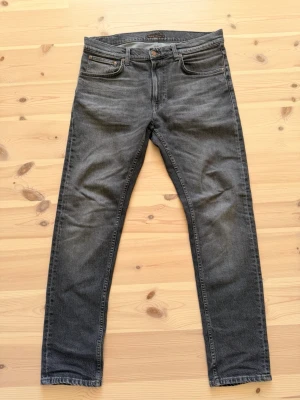 Grå slim fit jeans från Nudie - Snygga grå slim fit jeans från Nudie med klassisk femficksdesign och subtila slitningar. Jeansen är modell lean dean i storlek w34 L32