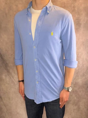 Ljusblå Ralph Lauren Skjorta feather weight mesh - Stl S - RIKTIGT FET RL SKJORTA I FÄRGEN LJUSBLÅ, med gul pony!, perfekt till sommaren som närmar sig! 🏖️🌊 | Mycket bra skick: 8,5/10, finns fläck på bröstet (syns men inte mycket) ! | Stl: S |  Modellen är 176cm och väger 75kg,  | Hör av dig vid frågor // Galgen 🫡