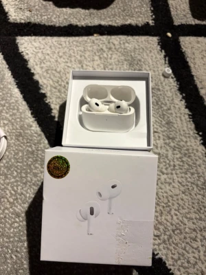 Apple AirPods Pro 2 (ANC)  - Säljer ett par vita Apple AirPods Pro 2 med laddningsetui. Hörlurarna är in-ear och har en stilren, kompakt design i plast. Perfekta för dig som vill ha grymt ljud och smidig anslutning till din iPhone eller andra Apple-enheter.